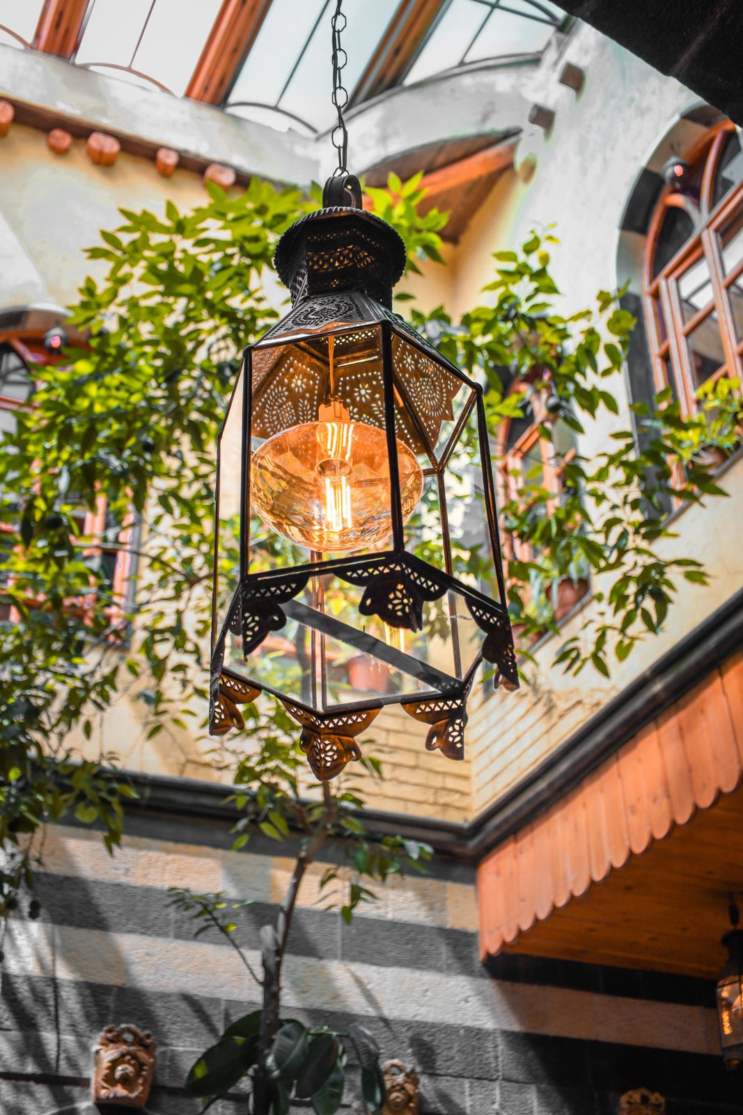 Hanging lantern glowing in a courtyard with plants